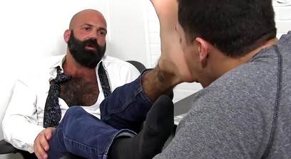 Bald bearded hunk foot worshipped and licked by young lad