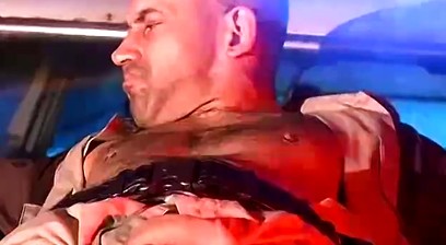 Officer Derek da Silva bound to the hood of a car
